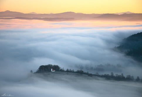 A small church rising from the dense morning fog (photograph).